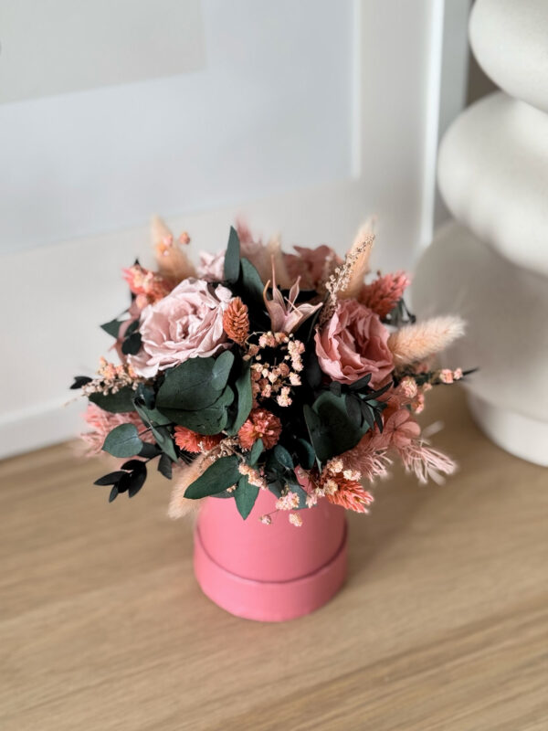 Flowerbox z suszonych i stabilizowanych kwiatów w odcieniach różu, brzoskwini i ciemnej zieleni w różowym pudełku